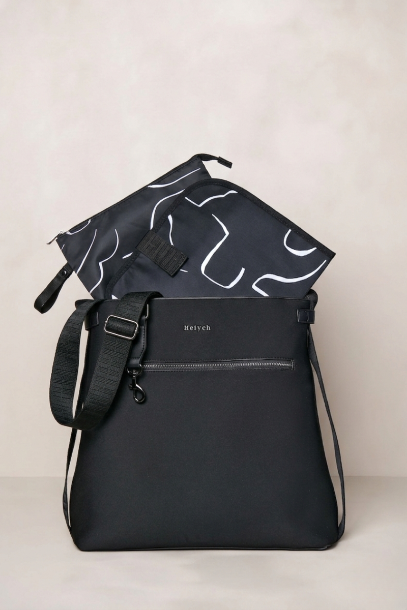 Black shoulder bag with a smaller black and white patterned pouch on a light background