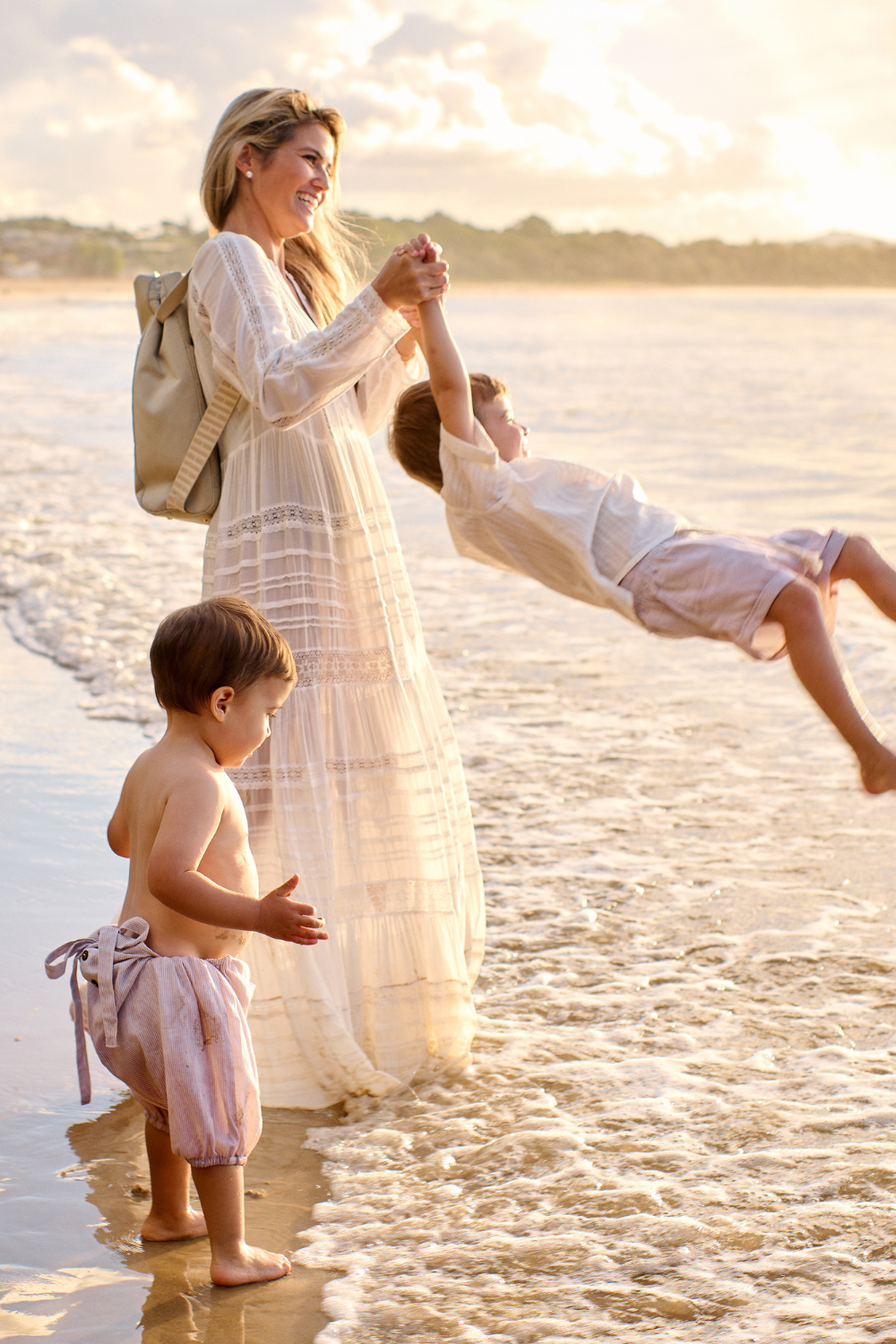 Mother Laura King carrying her children holding H Bag as a backpack at the beach