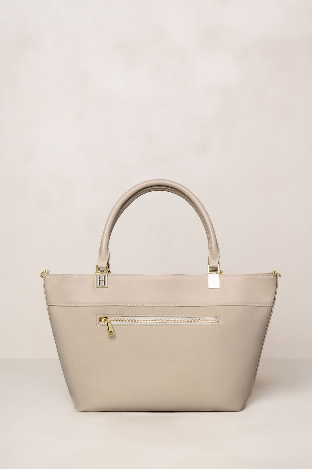 Beige taupe handbag with gold accents on a light beige background
