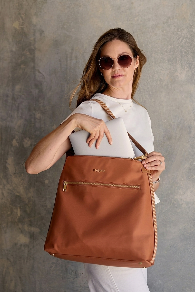 Woman holding a cognac brown nylon bag against a concrete background
