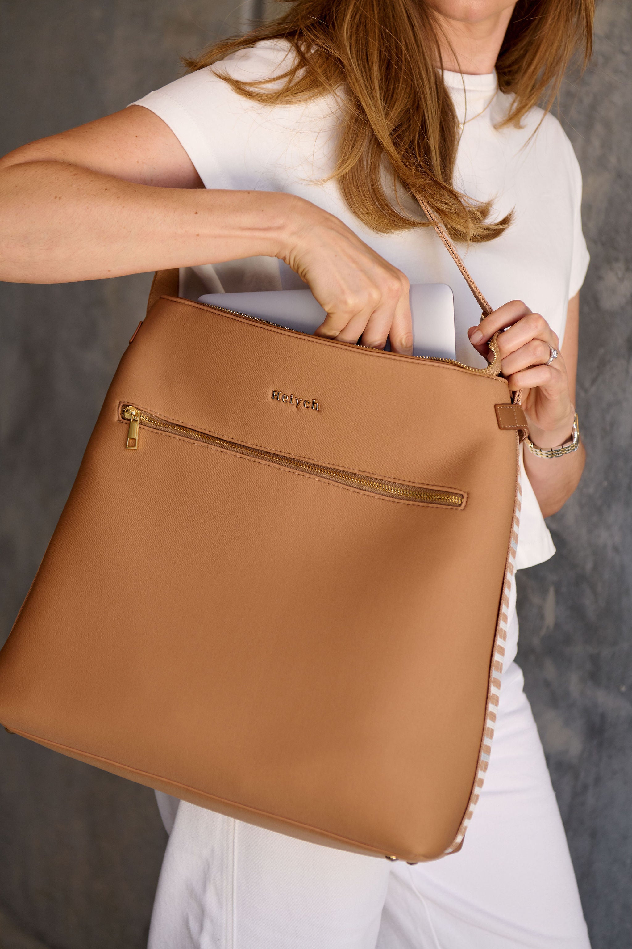 Woman holding a tan brown bag with a neutral background