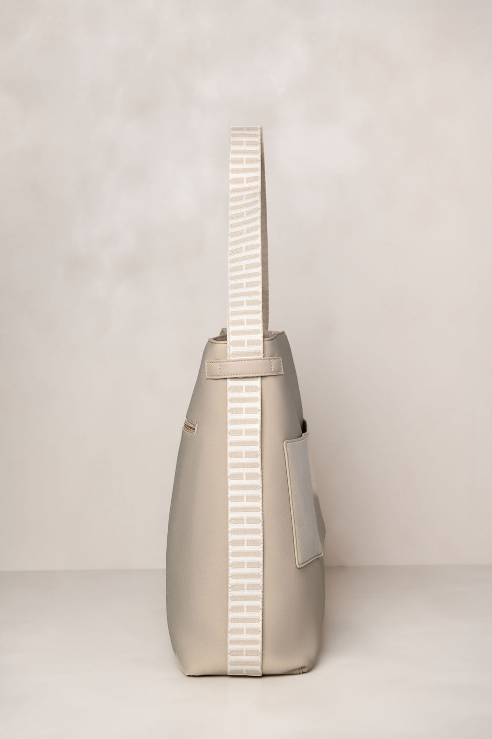 Beige taupe handbag with a strap on a light gray background