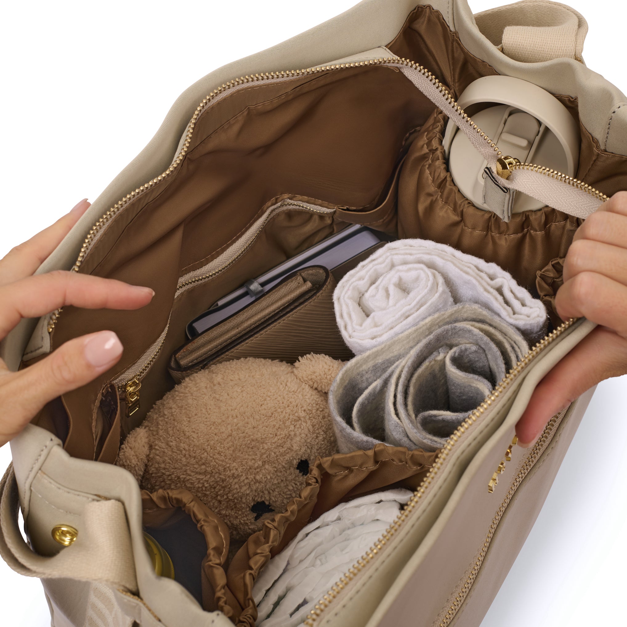 Open baby bag showing neatly organised compartments with diapers, a drink bottle, change of clothes, and a small toy.