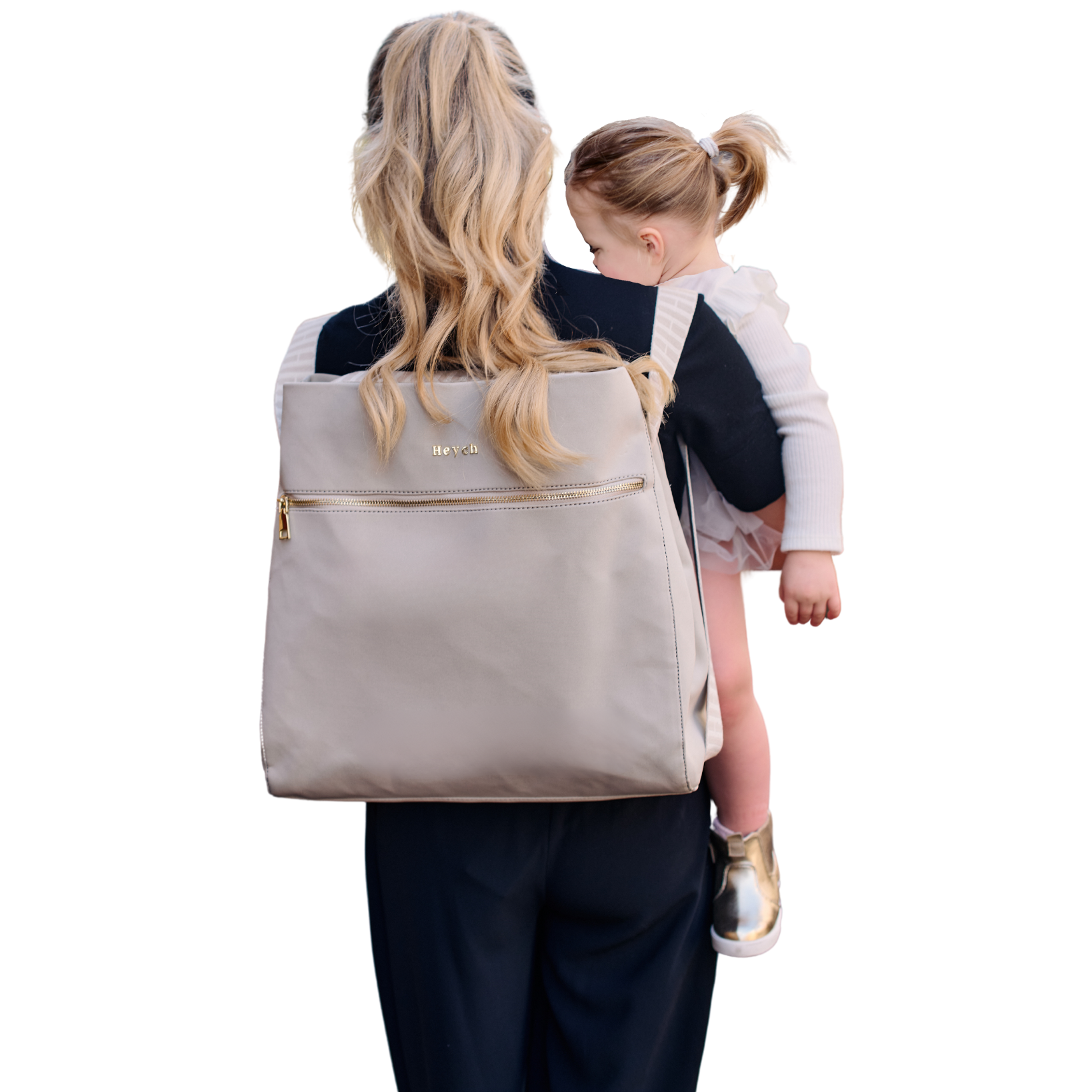 Mum holding baby girl and carrying stone taupe neoprene backpack bag with gold metal hardware.